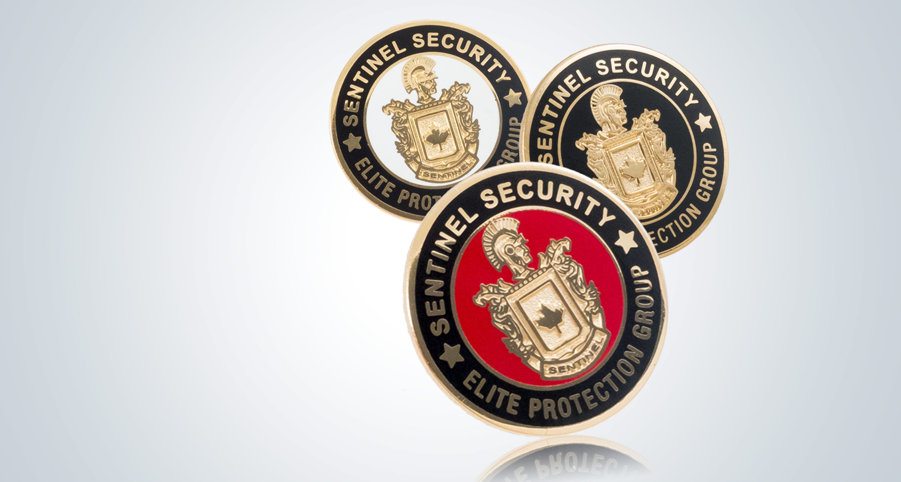 Three custom made pins arranged on a soft gray background.